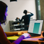 Commerçante qui consulte sur son ordinateur portable les résumés IA de Google derrière le comptoir de sa boutique