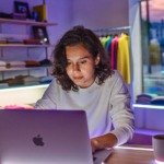 Commerçante qui prépare ses prix du Black Friday dans Shopify Rollouts sur un ordinateur portable, derrière le comptoir de sa boutique