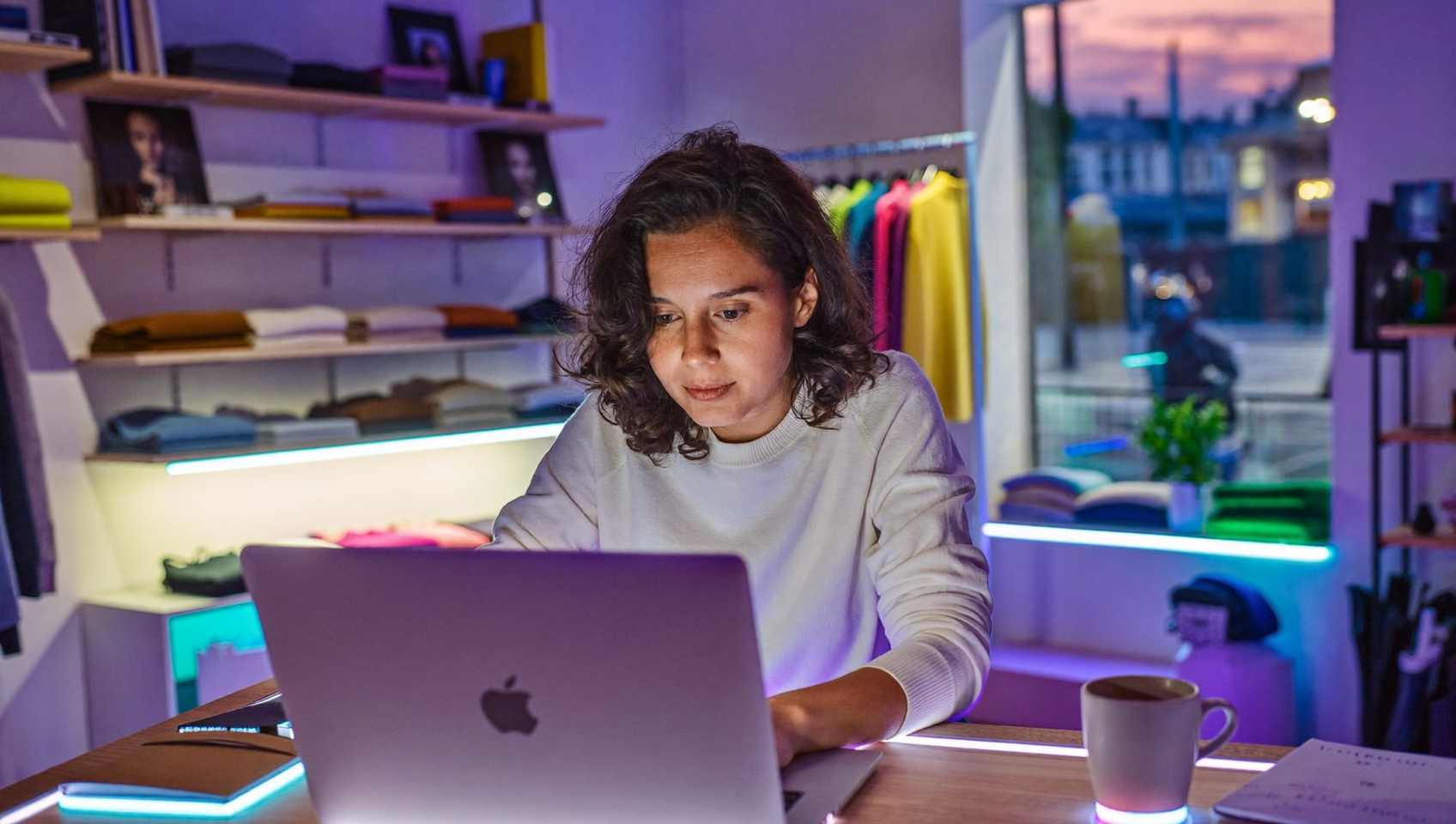 Commerçante qui prépare ses prix du Black Friday dans Shopify Rollouts sur un ordinateur portable, derrière le comptoir de sa boutique
