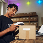 Commerçante qui scanne un code-barres avant de vérifier ses GTIN Shopify sur son ordinateur