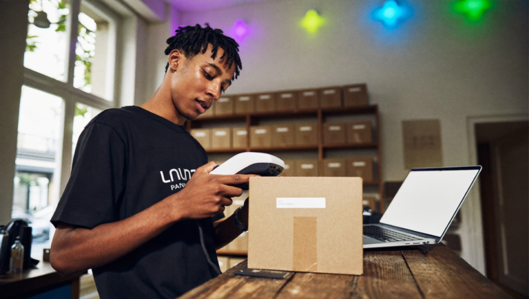 Commerçante qui scanne un code-barres avant de vérifier ses GTIN Shopify sur son ordinateur