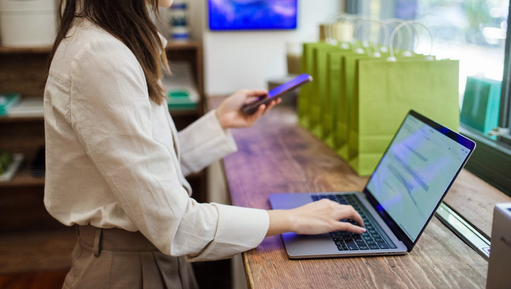 Commerçante qui vérifie les moyens de paiement Shopify sur son smartphone derrière le comptoir de sa boutique