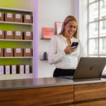 Commerçante vérifiant le réglage Sourced videos Performance Max sur son ordinateur portable derrière son comptoir