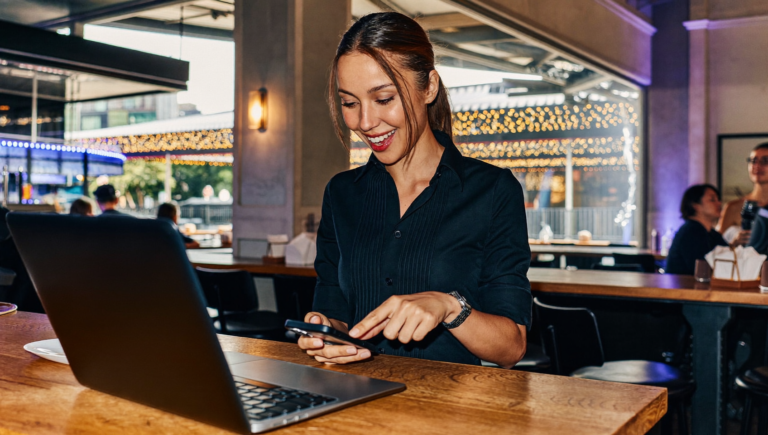 Gérante de restaurant sécurisant son Meta Account avec son empreinte digitale sur smartphone derrière le comptoir