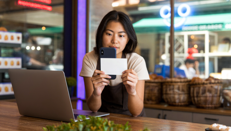 Une boulangère prépare la vérification Google Business Profile avec son smartphone derrière son comptoir